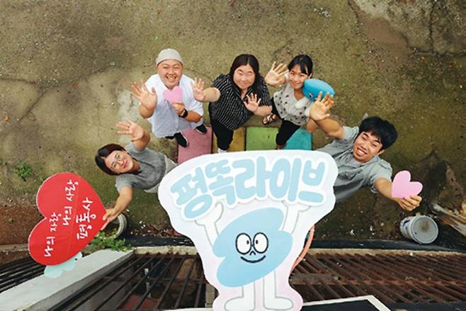 청년 활동가들이 청년 온라인 네트워크 ‘평화똑똑이’의 마스코트인 ‘평또기’를 농구 골대에 올려놓은 뒤 손을 흔들며 환하게 웃고 있다. 평또기는 박하영 활동가가 직접 디자인했다.