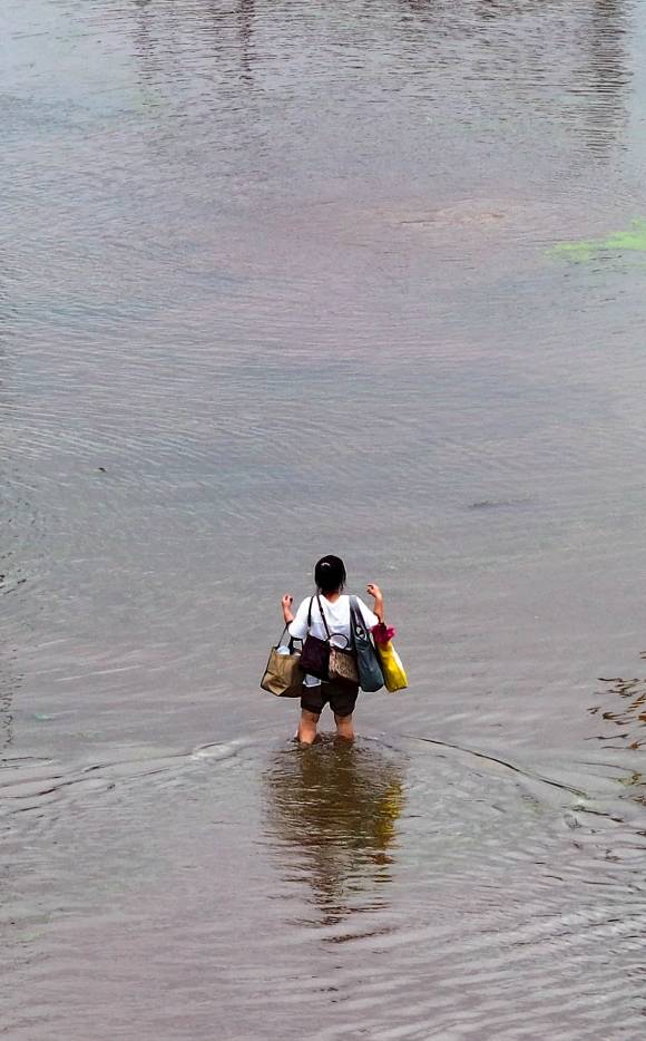 ‘물 폭탄’에 갇혔다 - 10일 대구에 쏟아진 폭우로 동구 금호강 일대가 범람하면서 시민들이 고립되는 사고가 잇따른 가운데 한 마을 주민이 양팔 가득 가방에 짐을 챙겨 침수된 도로를 따라 이동하고 있다. 이날 소방당국은 헬기를 투입해 금호강 일대 마을 주민 30여명을 구조했다. 대구 연합뉴스
