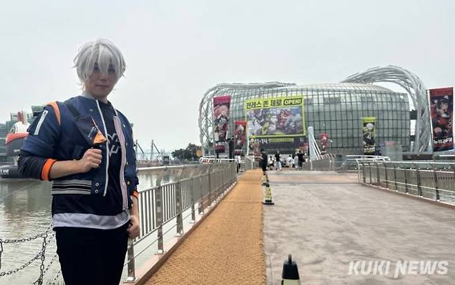 로프꾼인 와이즈 코스튬을 한 최훈씨가 12일 젠레스 존 제로 오프라인 행사장을 배경으로 사진을 찍고 있다. 사진=유채리 기자