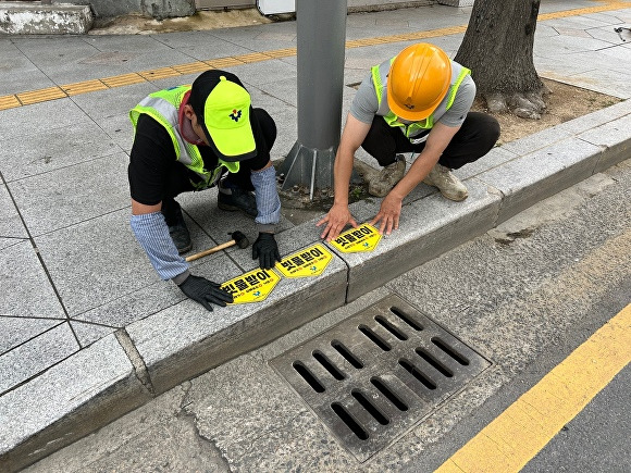 대구 중구청 직원들이 빗물받이 위치 스티커를 부착하고 있다. [사진=중구청]