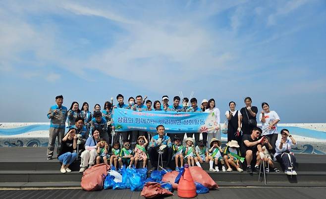 삼표시멘트 직원들과 삼척경찰서 직장 어린이집 원생들이 지난 11일 덕산해수욕장에서 해양정화 활동을 펼친 뒤 기념촬영을 하고 있다. 삼표시멘트 제공