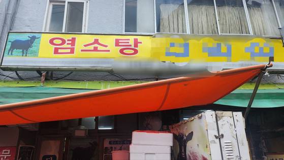 A storefront sign reads ″black goat soup,″ though traces of the old sign ″bosintang″ are still visible. [JOONGANG ILBO]