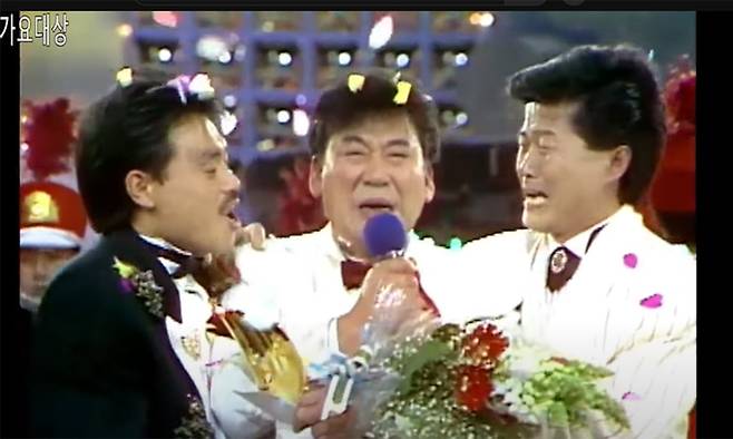 1989년 KBS 가요대상 시상식에서 대상을 수상한 현철이 감격한 모습으로 동료 태진아(오른쪽), 김흥국(왼쪽)과 함께 자신의 대표곡이 된 ‘봉선화 연정’을 부르고 있다. KBS 화면 캡처