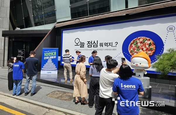 아이센스 본사 앞에서 임직원들이 직장인 대상 '케어센스 에어' 10만대 판매 기념 행사를 하고 있다.