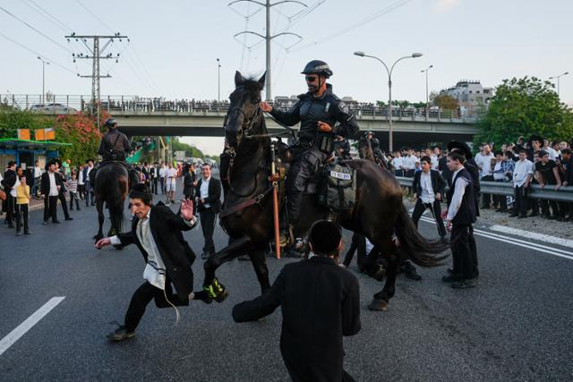 이스라엘 텔아비브 인근 브네이 브락에서 16일 이스라엘 기마경찰이 고속도로를 점거한 채 징병 반대 시위 중인 초정통파 유대인들을 해산시키고 있다. 이스라엘군은 지난달 25일 초정통파에 대한 병역면제가 부당하다는 대법원의 판결에 따라 다음 주부터 초정통파 유대교도에게 입영통지서를 보내기로 했다. 브네이 브락=AP 연합뉴스