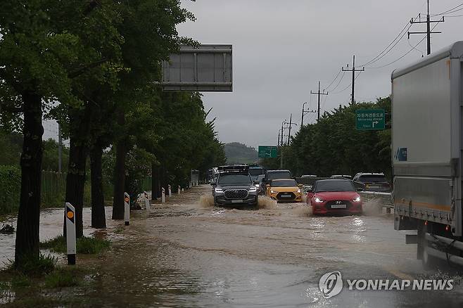 침수된 판문점 가는 길 (파주=연합뉴스) 임병식 기자 = 경기북부 접경지에 호우경보가 내린 17일 오전 경기도 파주시 문산읍에서 1번 국도가 일부 물에 잠겨 차량이 침수 지대를 피해 거북이 운행을 하고 있다. 2024.7.17 andphotodo@yna.co.kr