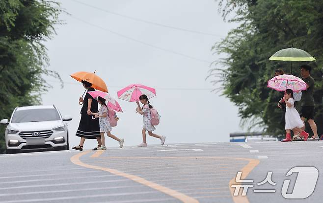 비가 내리는 19일 오전 광주 광산구 신창지구에서 학생들이 부모님의 손을 잡고 등굣길 발걸음을 재촉하고 있다. 2024.7.19/뉴스1 ⓒ News1 김태성 기자