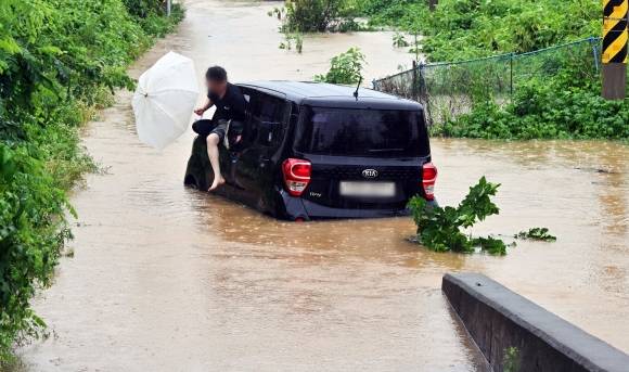필사의 탈출 - 수도권 등 중부지방에 물폭탄이 쏟아지면서 피해가 극심한 가운데 18일 경기 화성시 황계동에 있는 한 도로의 침수된 차량에서 운전자가 대피하고 있다. 뉴시스