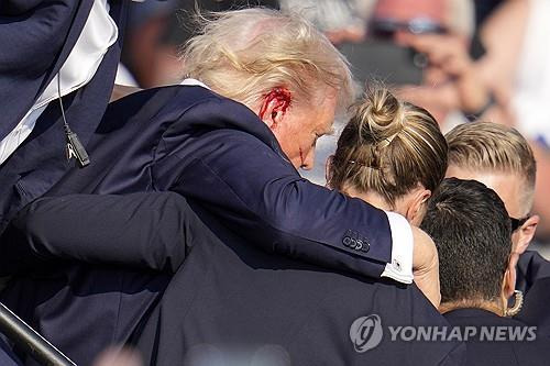 피격 후 경호원들에 둘러싸여 무대에서 내려가는 트럼프 전 대통령 [AP=연합뉴스 자료사진. 재판매 및 DB 금지]