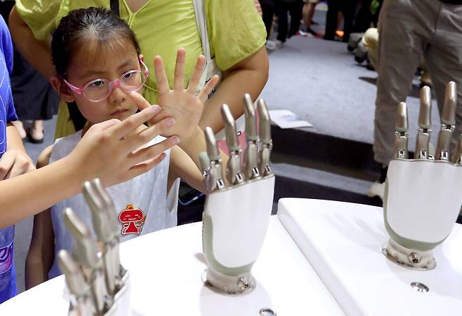 지난 5일 중국 상하이에서 열린 2024 세계 에이아이(AI) 콘퍼런스에서 한 어린이가 인공지능 기계 손을 살펴보고 있다. 신화 연합뉴스