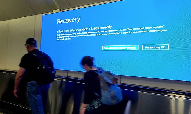 지난 20일(현지시간) 미국 워싱턴 DC 덜레스 국제공항에서 여행객들이 마이크로소프트 윈도우 오류 메시지가 표시된 화면을 지나가고 있다. UPI연합뉴스