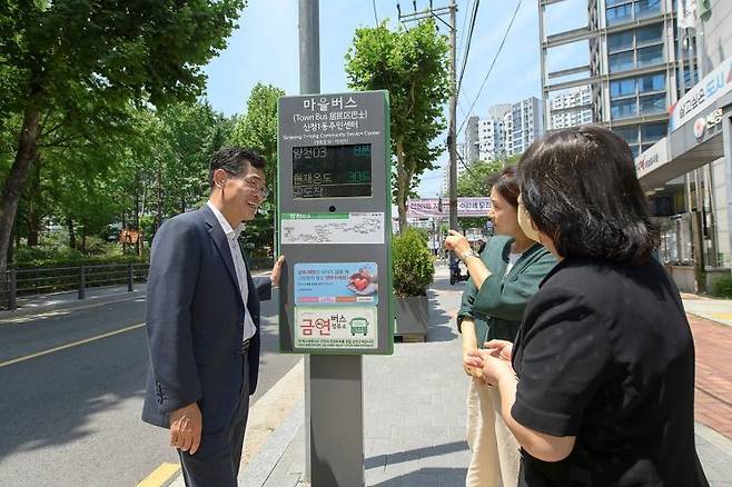 양천구 마을버스 정보안내단말기를 이용하는 주민과 이기재 양천구청장(사진 왼쪽). 양천구 제공.