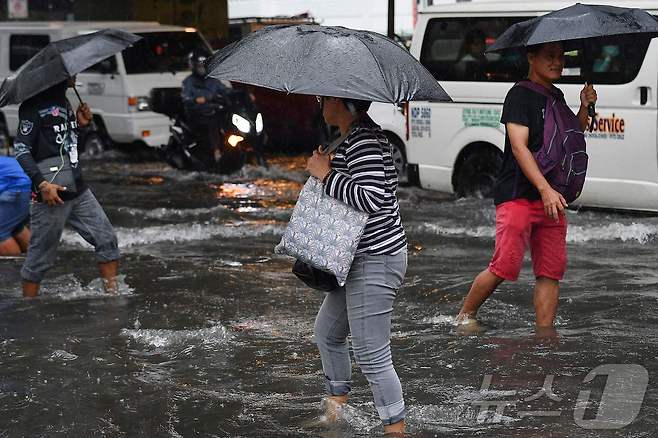 필리핀 마닐라 시민들이 23일 3호 태풍 '개미'가 몰고온 폭우로 물이 차오른 마닐라 거리를 걷고 있다. 2024.07.23 ⓒ AFP=뉴스1 ⓒ News1 권진영기자