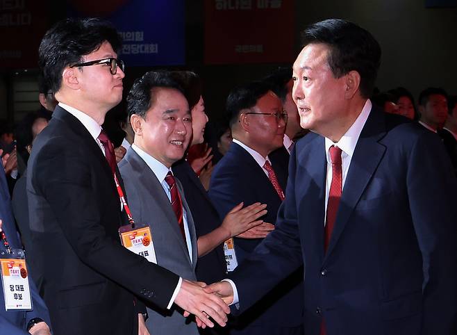 President Yoon Suk Yeol (right) shakes hands with Han Dong-hoon at the People Power Party convention in Ilsan, Gyeonggi Province, on Tuesday. (Yonhap)