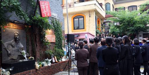 24일 서울 종로구 대학로 아르코꿈밭극장(옛 학전) 마당에서 유족과 추모객들이 ‘김광석 추모비’ 옆에 김민기 영정을 놓고 묵념하고 있다. 뉴스1