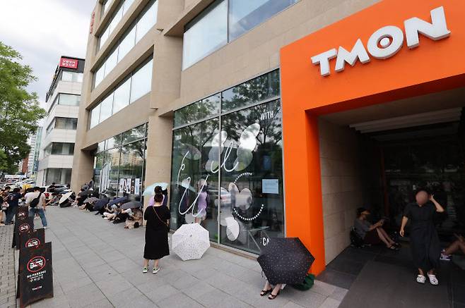 싱가포르 기반의 전자상거래(이커머스) 플랫폼 큐텐 계열사인 위메프와 티몬 정산 지연 사태가 점차 확산되고 있는 25일 서울 강남구 티몬 본사 앞에서 환불을 원하는 피해자들이 우산을 쓰고 사측을 기다리고 있다 .(사진=연합뉴스)