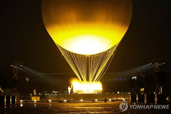 열기구 모양의 성화대 (파리 AP=연합뉴스) 페레크와 리네르가 27일(한국시간) 프랑스 파리의 튈르리 정원에 있는 '열기구 성화대'에 불을 붙이고 있다.