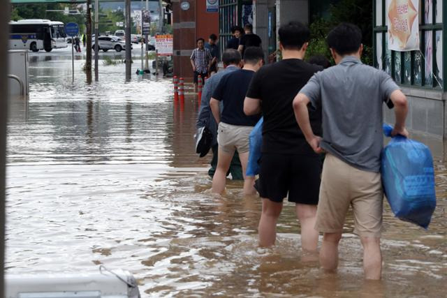 지난해 7월 24일 오전 전남 목포시 석현동에서 금융기관 직원들이 폭우로 침수된 거리를 줄지어 걸으며 출근하고 있다. 목포=연합뉴스