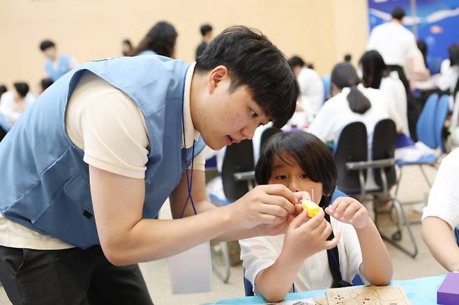 포스코퓨처엠 직원이 30일 포항 포스코 본사 대강당에서 열린 ‘푸른꿈 환경캠프’에 멘토로 나서 어린이와 함께 전기차 모형을 제작하고 있다. 사진=포스코퓨처엠