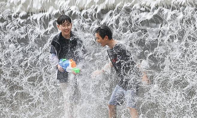 전국 대부분 지역에 폭염 특보가 내려진 30일 오전 경기도 수원시 영통구 광교호수공원 신비한 물너미를 찾은 학생들이 시원하게 쏟아지는 물을 맞으며 더위를 식히고 있다. 연합뉴스