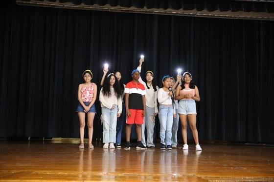 열악한 환경에 놓인 미국 이민자 가정 학생들이 25일 미국 매사추세츠주 브록턴의 한 중학교에서 열린 여름 캠프 마무리 공연에서 월드비전 자원봉사자들과 '아이 해브 어 드림' 노래를 열창하고 있다. 사진 월드비전