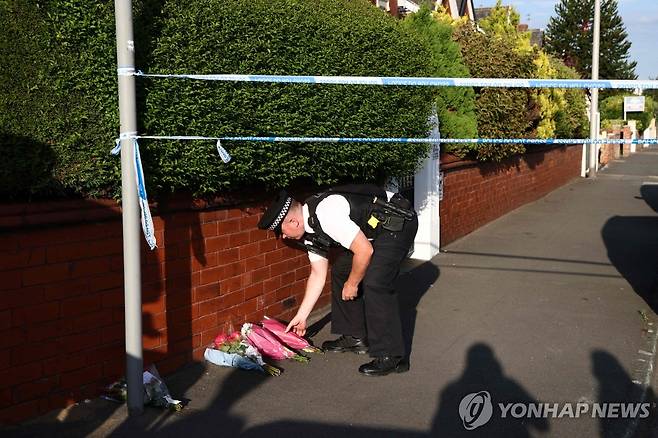 사우스포트 사건 현장 인근 (사우스포트 AFP=연합뉴스) 경찰관이 29일(현지시간) 흉기 공격이 발생한 사우스포트 하트스트리트에 사람들이 가져온 꽃을 놓아두고 있다.