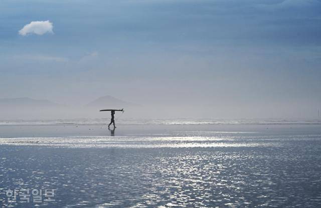 한 서퍼가 바닷물이 찰랑거리는 다대포해수욕장을 가로지르고 있다. 수시로 해무가 올라 몽환적인 분위기를 자아낸다.