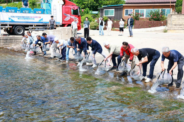 ▲(왼쪽 다섯번째)손병복 울진군수가 죽변면 골장항에서 참석자들과 함께 어린 강도다리,조피볼락을 방류하고 있다.ⓒ울진군청