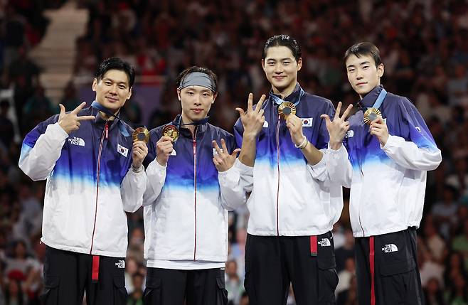 구본길(왼쪽부터), 박상원, 오상욱, 도경동이 7월 31일(현지시각) 프랑스 파리 그랑 팔레에서 열린 2024 파리 올림픽 펜싱 남자 사브르 단체 시상식에서 금메달을 목에 걸고 3연패를 의미하는 포즈를 취하고 있다. /뉴시스