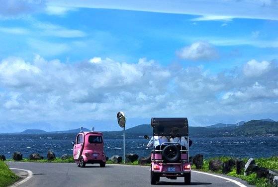 우도 해안도로를 질주하는 전동차. 앞엣것은 삼륜차고, 뒤엣것은 4륜차다. 손민호 기자