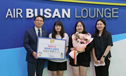 1일 김해공항 에어부산 라운지에서 에어부산 마호진(왼쪽에서 첫 번째) 영업본부장과 관계자가 10만 번째 입장객에게 국제선 왕복항공권과 기념품을 전달한 후 기념 촬영을 하고 있다. [사진=에어부산]
