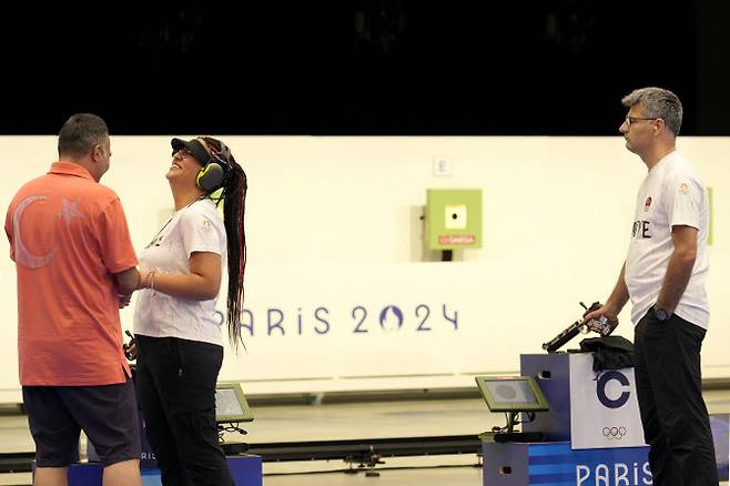 30일(현지시간) 샤토루 슈팅센터에서 열린 사격 혼성 공기권총 10m 금메달 결정전 중 주어진 휴식 시간에서 튀르키예의 유수프 디케츠(51)가 함께 조를 이룬 세볼 일라이타 타르한(24)과 코치가 대화하는 모습을 보고 있다. (사진=AP통신)