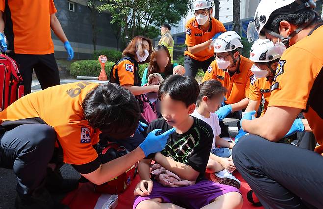 1일 오전 인천 서구 청라 한 아파트 지하 주차장 전기차에서 발화한 것으로 추정되는 화재가 발생 연기를 흡입한 어린이들이 대피해 소방관들의 진료를 받고 있다. /연합뉴스