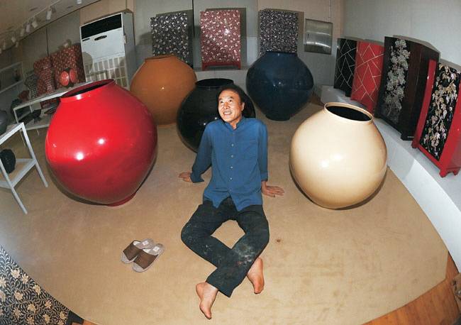 손대현 장인이 지난달 31일 경기 광주시 곤지암읍 수곡공방 2층 전시설에서 달항아리와 가구 등 자신이 만든 나전칠기 작품 사이에 앉아 있다.작은 사진은 1층 공방에서 나전 칠기 표면을 연마하는 모습. 백동현 기자