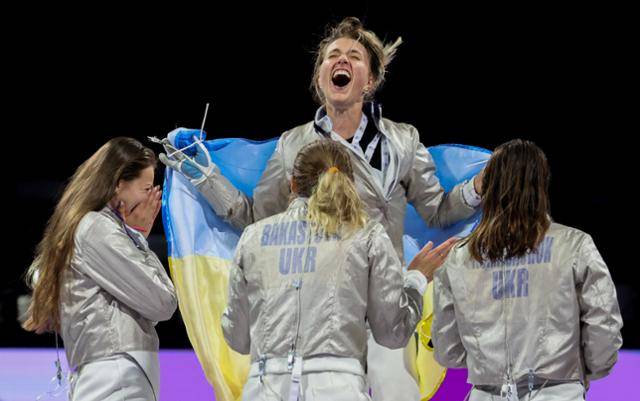 우크라이나의 올하 하를란(가운데)이 3일(현지시간) 프랑스 파리 그랑팔레에서 열린 2024 파리 올림픽 펜싱 여자 사브르 단체전 결승전에서 금메달을 딴 뒤 우크라이나 국기를 두른 채 동료 선수들과 함께 기뻐하고 있다. 파리=서재훈 기자