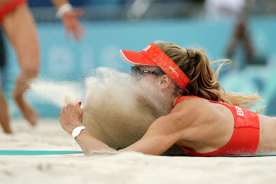 Switzerland's Nina Brunner lands in the sand after diving for a shot in a beach volleyball match against France in Paris on Saturday.  [AP/YONHAP]