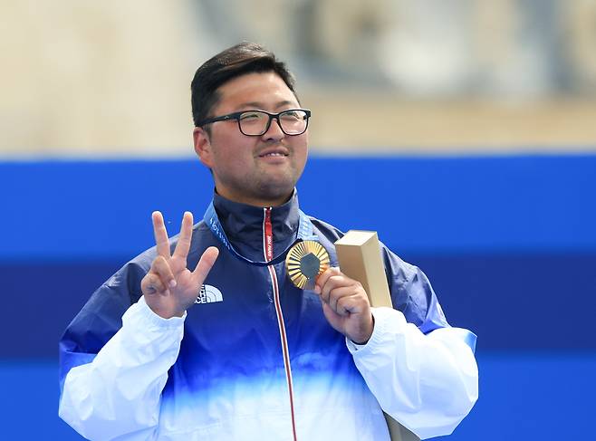 대한민국 남자 양궁 대표팀 김우진 선수가 4일(현지 시각) 프랑스 파리 앵발리드에서 열린 2024 파리올림픽 남자 양궁 개인전 시상식에서 금메달을 들어보이면서 오른손으로 숫자 3을 나타내고 있다. 대회 3관왕이라는 의미다. /뉴스1