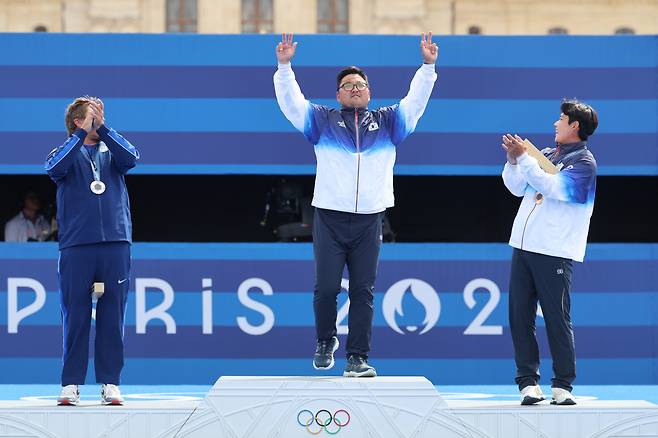 Kim Woo-jin (center) poses during the medal ceremony of the men's individual archery event at the Paris Olympics at Invalides in Paris on Sunday, while his teammate Lee Woo-suk (right), and Brady Ellison applaud him. (Yonhap)