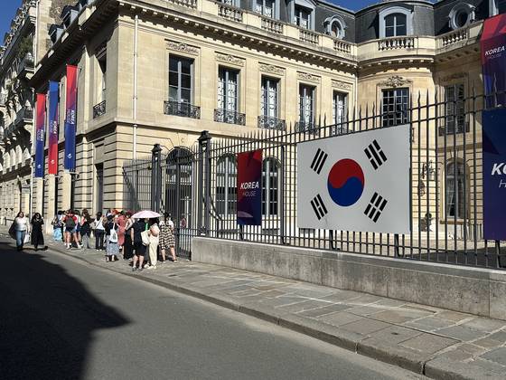 Visitors line up outside Korea House 30 minutes before the doors open in Paris on Monday.  [JIM BULLEY]
