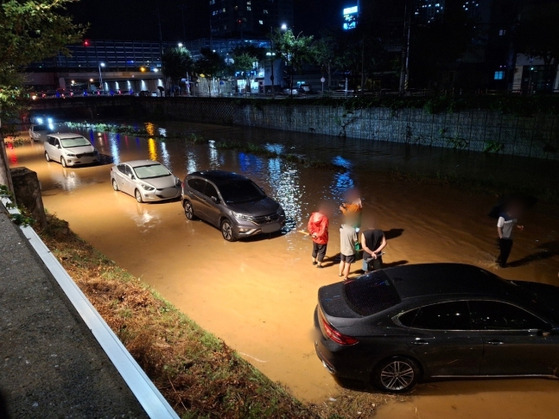 People abandon their vehicles in a flooded parking lot near Yanggeun Stream in Yangpyeong-gun, Gyeonggi, on Monday. [GYEONGGI FIRE AND DISASTER HEADQAURTER]