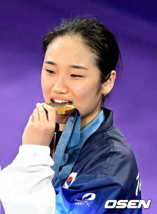 [OSEN=파리(프랑스), 최규한 기자] 5일(한국시간) '셔틀콕 여제' 안세영(22, 삼성생명)이 꿈에 그리던 올림픽 금메달을 목에 걸었다.세계 랭킹 1위 안세영은&nbsp;5일 오후(이하 한국시간) 프랑스 파리 포르트 드 라샤펠 경기장에서 열린 2024 파리올림픽 배드민턴 여자 단식 결승전에서 랭킹 9위 허빙자오(중국)를 2-0으로 꺾고 금메달을 획득 했다. &nbsp;한국 안세영이 시상식에서 금메달을 깨물고 있다. 2024.08.05 / dreamer@osen.co.kr