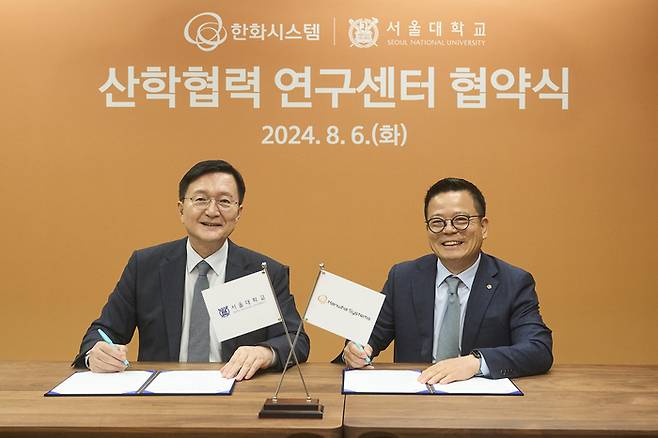 한화시스템과 서울대가 서울 관악구에 있는 서울대 캠퍼스에서 산학협력 업무협약(MOU)을 체결했다. 유홍림 서울대 총장(왼쪽)과 어성철 한화시스템 대표이사가 기념 촬영을 하고 있다. <한화시스템)</figcaption>
