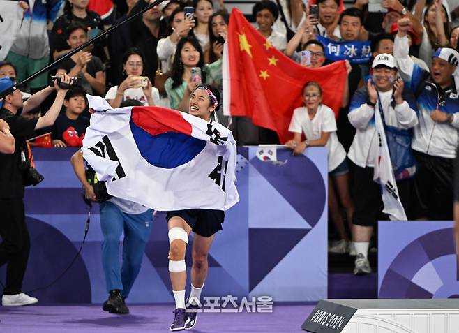 배드민턴 국가대표 안세영이 5일 프랑스 파리 포르트 드 라 샤펠에서 열린 2024 파리 올림픽 배드민턴 여자 단식 결승전에서 중국의 허빙자오를 꺾고 금메달을 딴 뒤 관중석에서 전해받은 태극기를 들고 코트를 뛰어다니고 있다. 파리 | 박진업 기자 upandup@sportsseoul.com