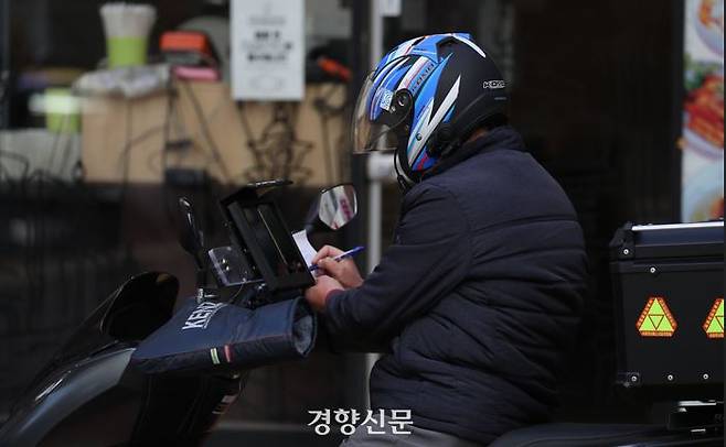 A delivery worker is writing something on the paper. Reporter Han Soo-bin