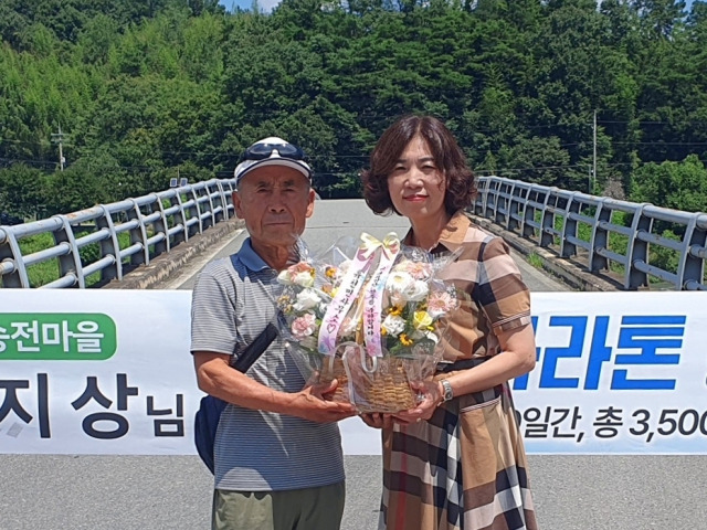 경남 함양군 휴천면 송전마을 원지상 씨가 미국 대륙 마라톤 횡단을 성공적으로 마무리하고 지난 1일 귀국하자 이선희 휴천면장이 축하 꽃바구니를 전달하고 있다. 사진제공=함양군