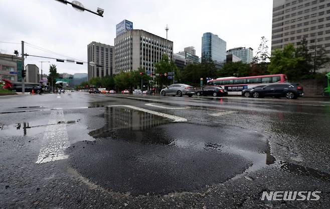 [서울=뉴시스] 김선웅 기자 = 지난달 21일 서울 종로구 경복궁역 1번출구 인근 도로에서 어제 발생한 도로 파임(포트홀) 복구가 완료돼 원활한 차량 통행을 보이고 있다. 2024.07.21. mangusta@newsis.com