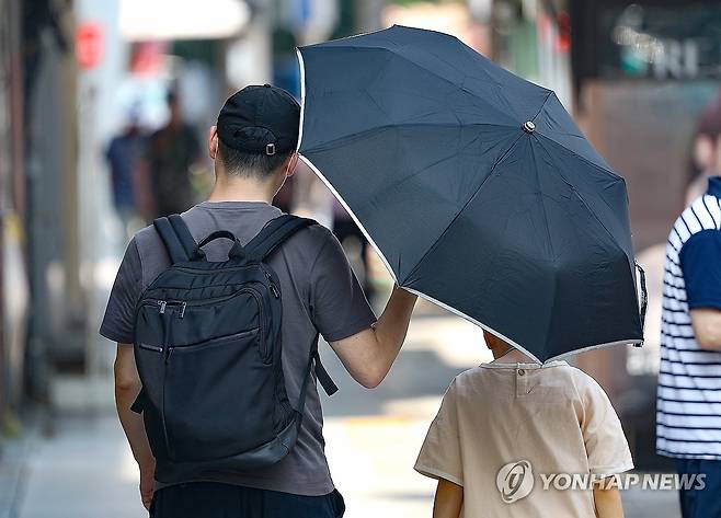 아빠의 마음 (대구=연합뉴스) 윤관식 기자 = 전국 대부분 지역에 폭염 특보가 이어진 9일 대구 중구 동성로에서 한 시민이 자녀에게 양산을 씌워주며 이동하고 있다. 2024.8.9 psik@yna.co.kr