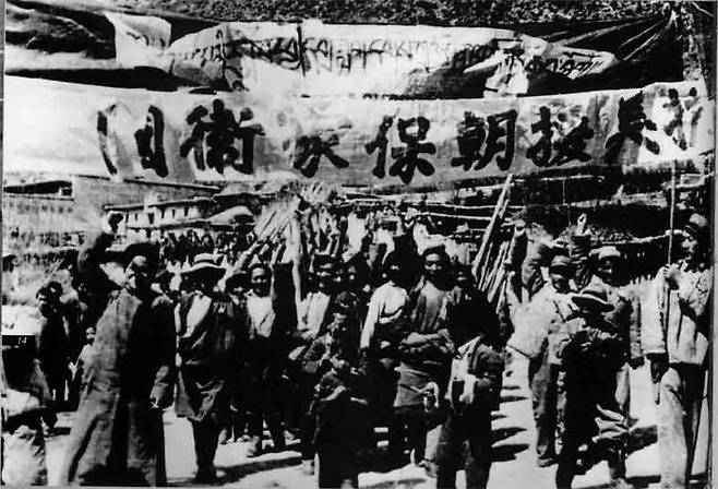 1950년 중국 인민지원군의 파병을 앞두고 중국의 한 거리에서 벌어진 지원 시위.  현수막엔 “항미원조(抗美援朝), 보가위국(保家衛國)”의 구호가 적혀 있다. “미국에 저항하고 조선을 도와주자. 가족과 나라를 보위하자.”