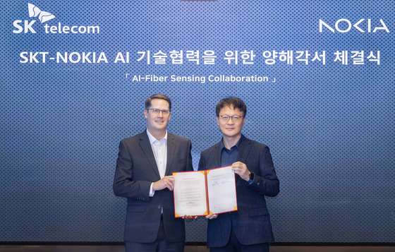 SK Telecom’s Ryu Jung-hwan, head of infrastructure strategy and technology, right, and John Harrington, Nokia’s senior vice president and head of network infrastructure sales for the Asia-Pacific region, pose for a photo after a signing ceremony at SK Telecom's headquarters in central Seoul on Wednesday. [SK TELECOM]