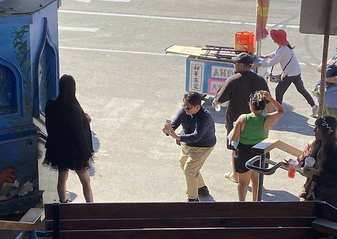 방시혁 하이브 의장이 수백억원대 저택이 있는 미국 LA에서 무릎을 굽혀가며 한 여성의 사진을 찍어주고 있다. 아프리카TV BJ ‘과즙세연’의 친언니로 방 의장과 친분이 있다고 한다. 최근 공개 석상에 나오지 않던 방 의장은 미국에 놀러 온 이 자매에게 맛집을 소개해줬다고./인터넷 커뮤니티